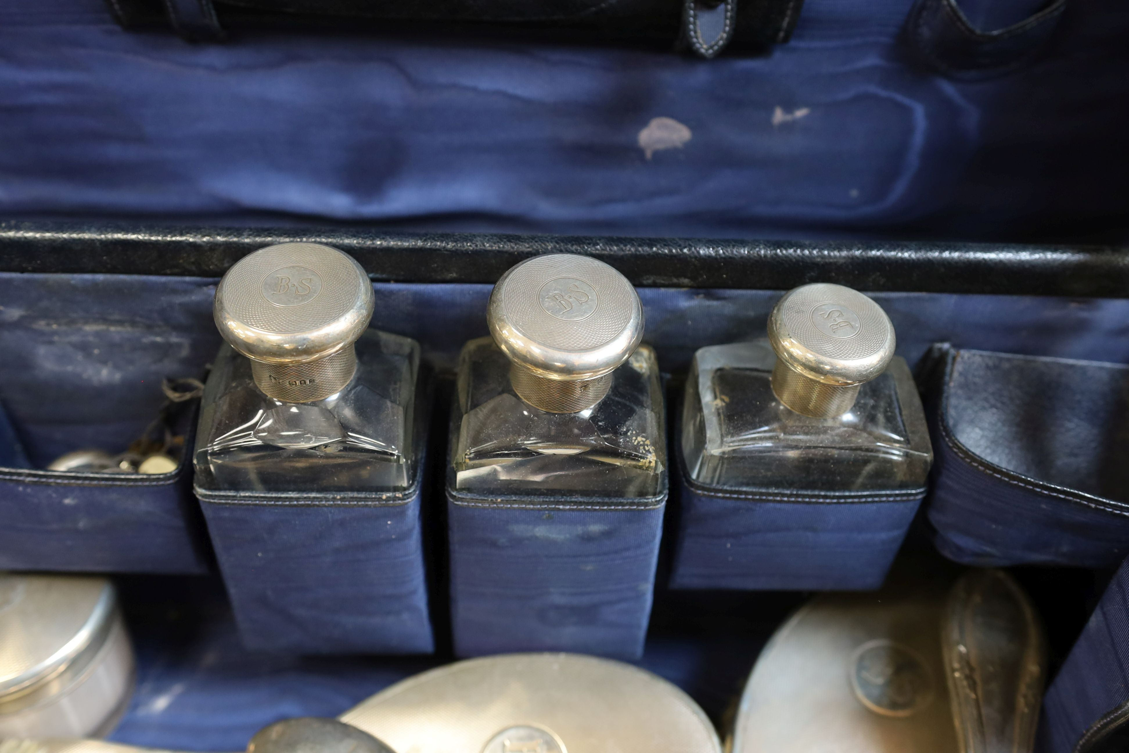 A 1930's part silver mounted glass toilet set , comprising eleven items, London, 1933 in a leather travelling case, together with five other associated accoutrements.